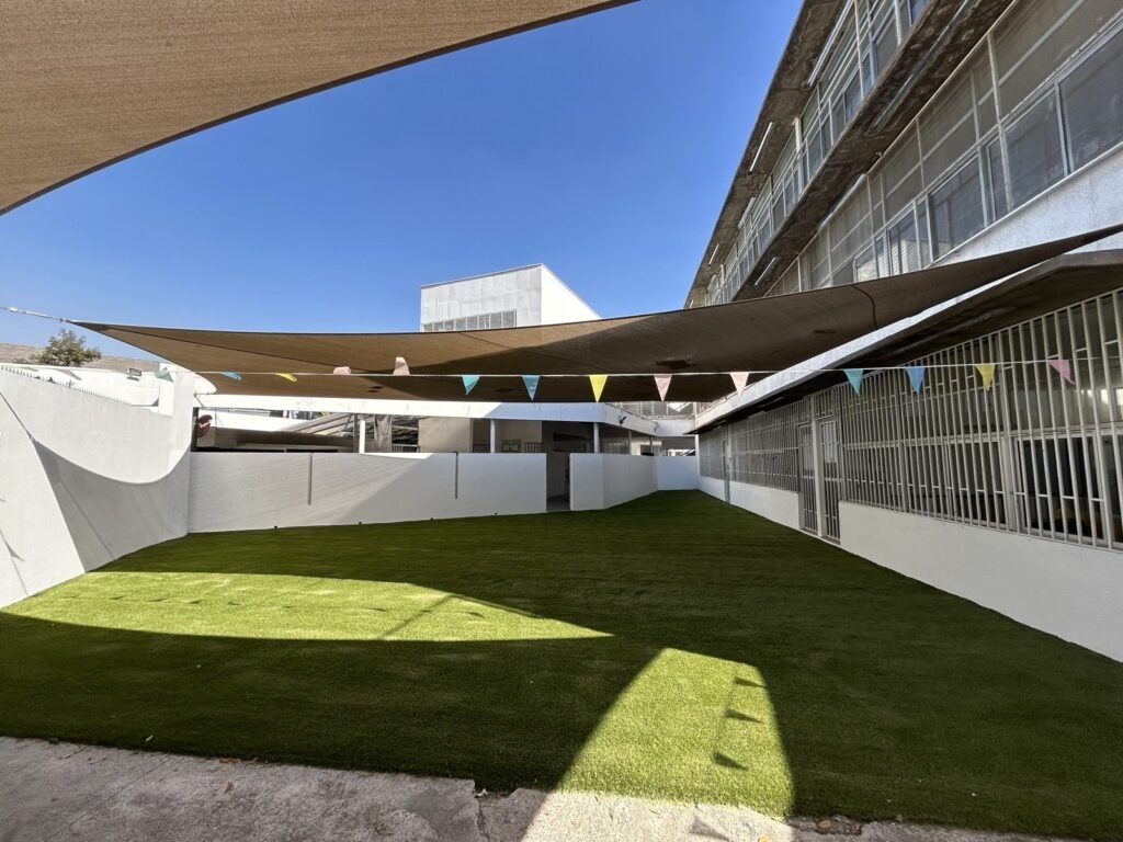 Patio de colegio con pasto sintético, vista desde la entrada