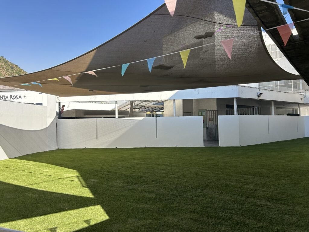 Pasto sintético instalado en patio de colegio con malla de sombra
